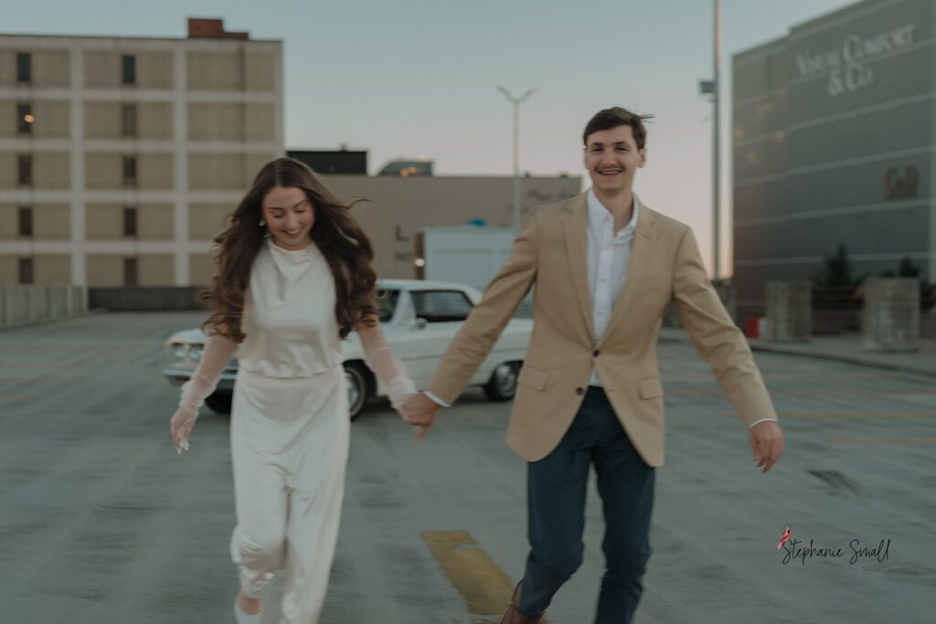 Couple running and laughing on a rooftop in Downtown High Point, NC during their engagement session