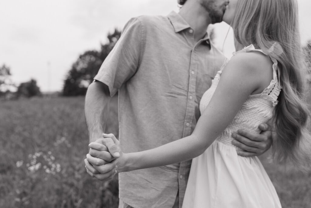 Couple walking hand-in-hand through a sunlit field at Price Park in Greensboro, NC during golden hour