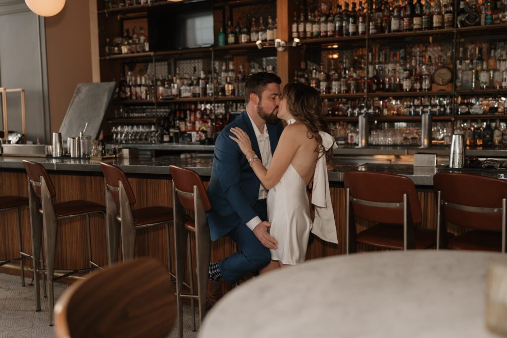 Engaged couple kissing by the bar inside the Kimpton Cardinal Hotel in Winston Salem, NC