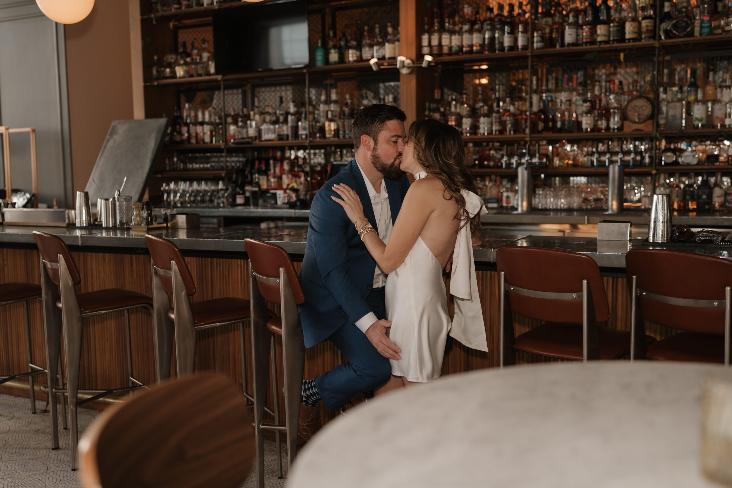 Engaged couple kissing by the bar inside the Kimpton Cardinal Hotel in Winston Salem, NC