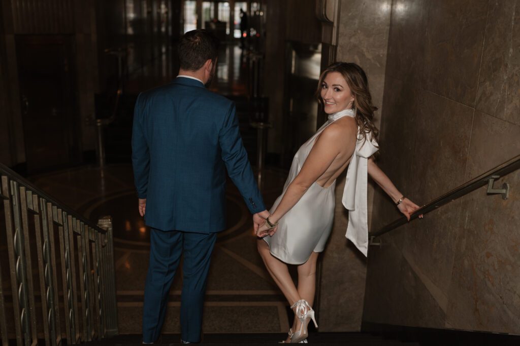 Engaged walking on the grand staircase inside the Kimpton Cardinal Hotel in Winston Salem, NC