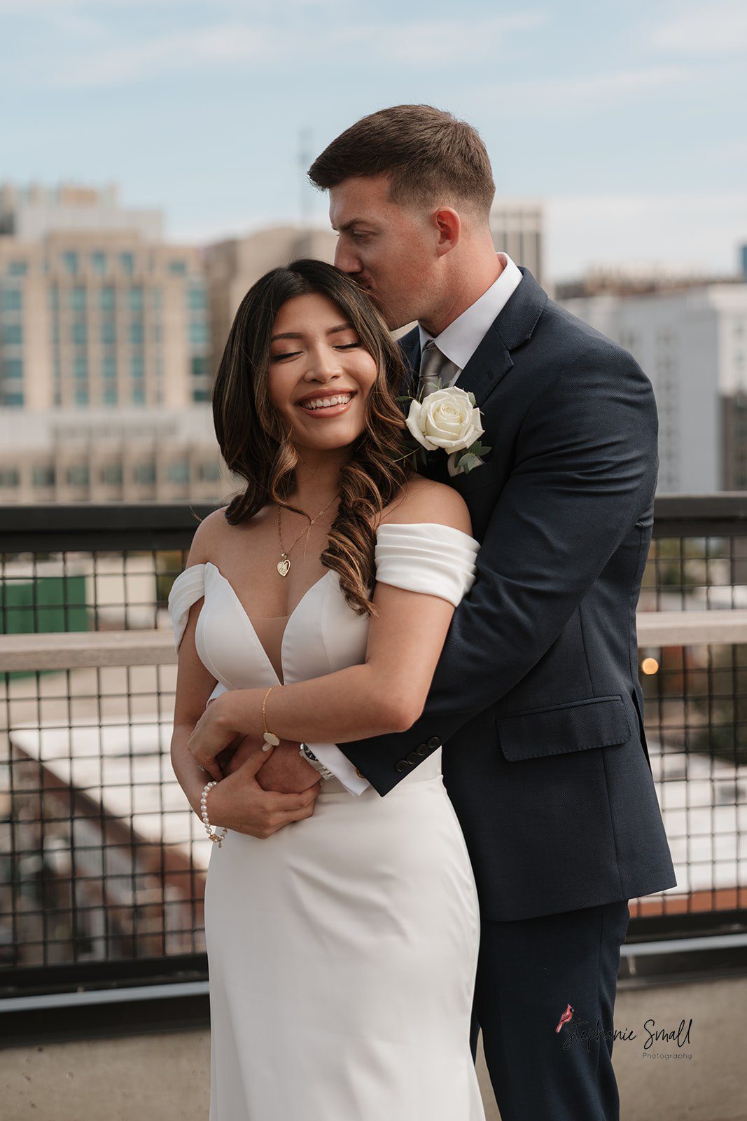 Bride and groom embracing on the rooftop during their La Terrazza Raleigh intimate wedding with skyline views