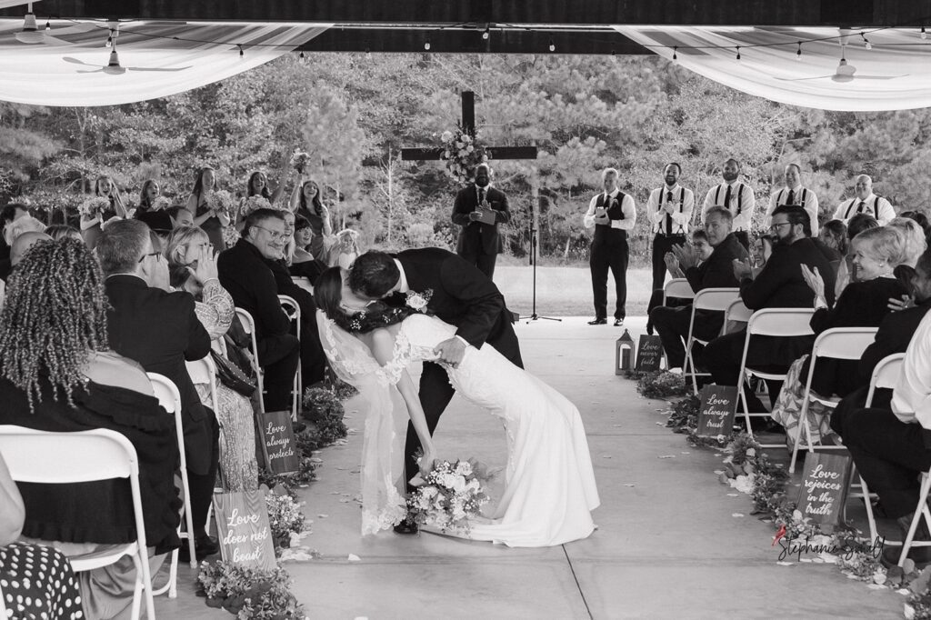 Bride and groom first kiss during ceremony at Oakland Farms Wedding Venue in Sanford NC